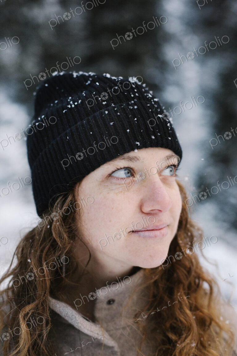 A woman in a black hat dusted with snow outdoors.