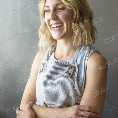 A woman in a blue work apron with arms folded, smiling. A woman in a blue work apron with arms folded, smiling.