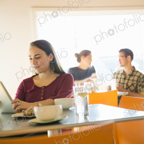 A woman in a coffee shop reading using a tablet computer. A woman in a coffee shop reading using a tablet computer.