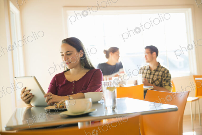 A woman in a coffee shop reading using a tablet computer.