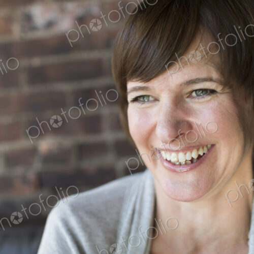 A woman in a coffee shop. Smiling. Head and shoulders.