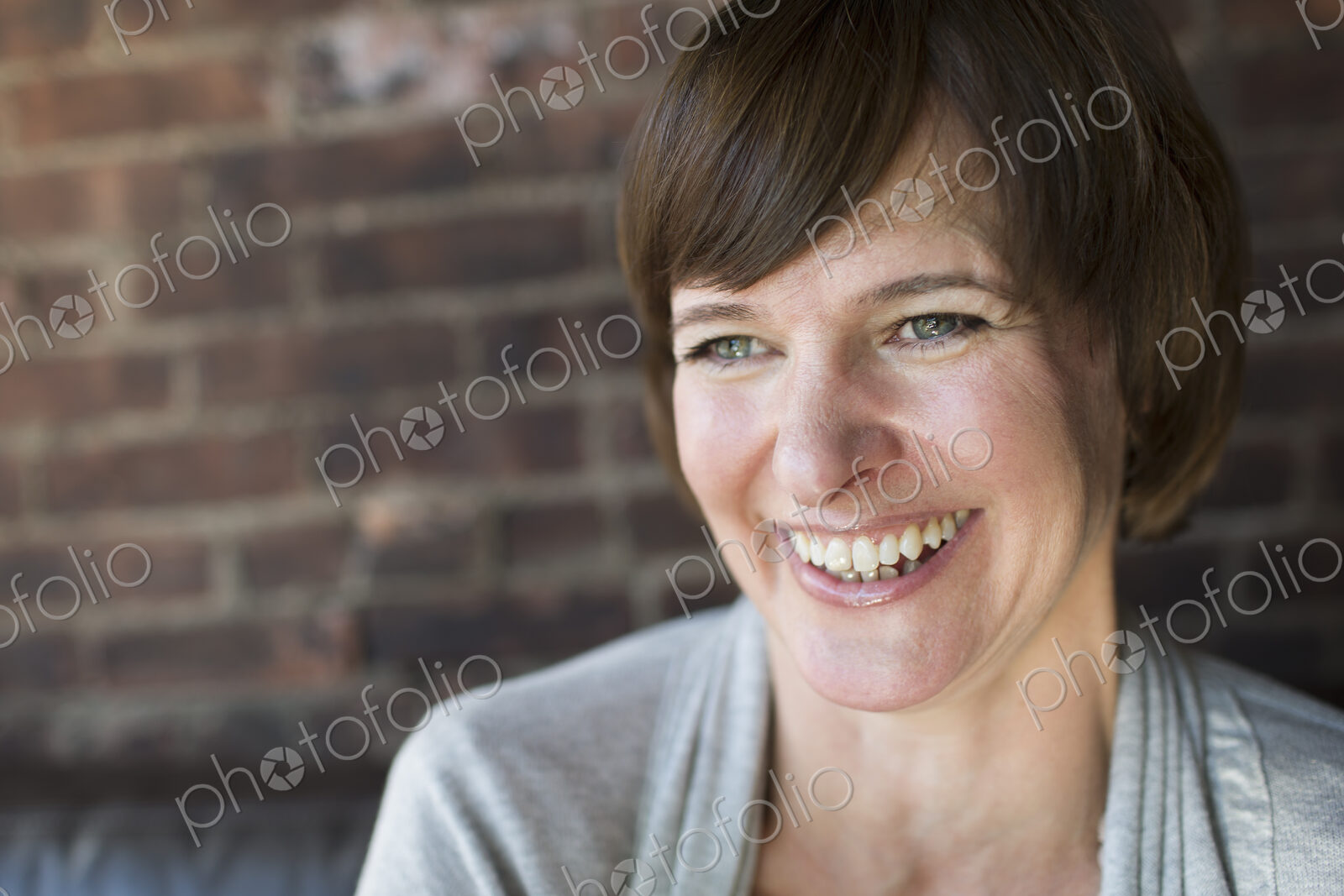 A woman in a coffee shop. Smiling. Head and shoulders.