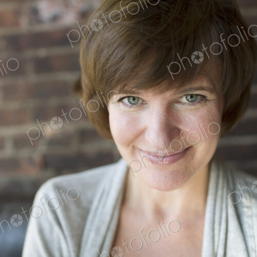 A woman in a coffee shop. Smiling. Head and shoulders.