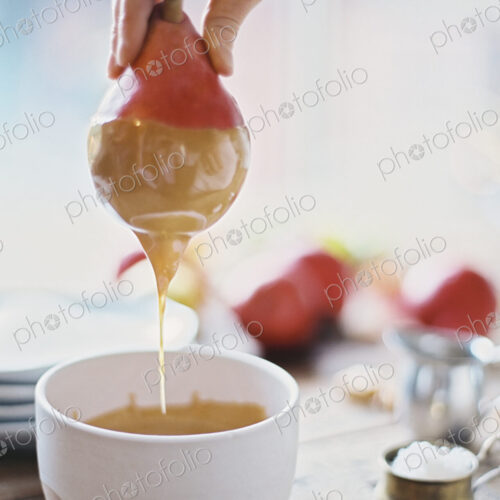 A woman in a domestic kitchen cooking. Dipping fresh organic pears into a sauce for… A woman in a domestic kitchen cooking. Dipping fresh organic pears into a sauce for…
