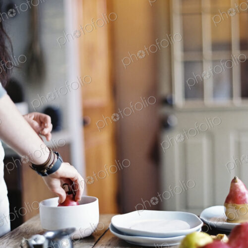 A woman in a domestic kitchen cooking. Dipping fresh organic pears into a sauce for… A woman in a domestic kitchen cooking. Dipping fresh organic pears into a sauce for…