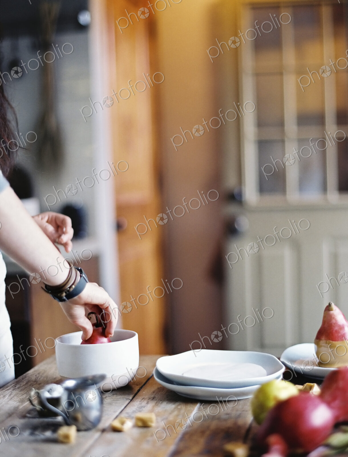 A woman in a domestic kitchen cooking. Dipping fresh organic pears into a sauce for…