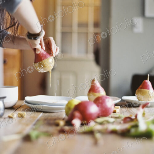 A woman in a domestic kitchen cooking. Dipping fresh organic pears into a sauce for… A woman in a domestic kitchen cooking. Dipping fresh organic pears into a sauce for…