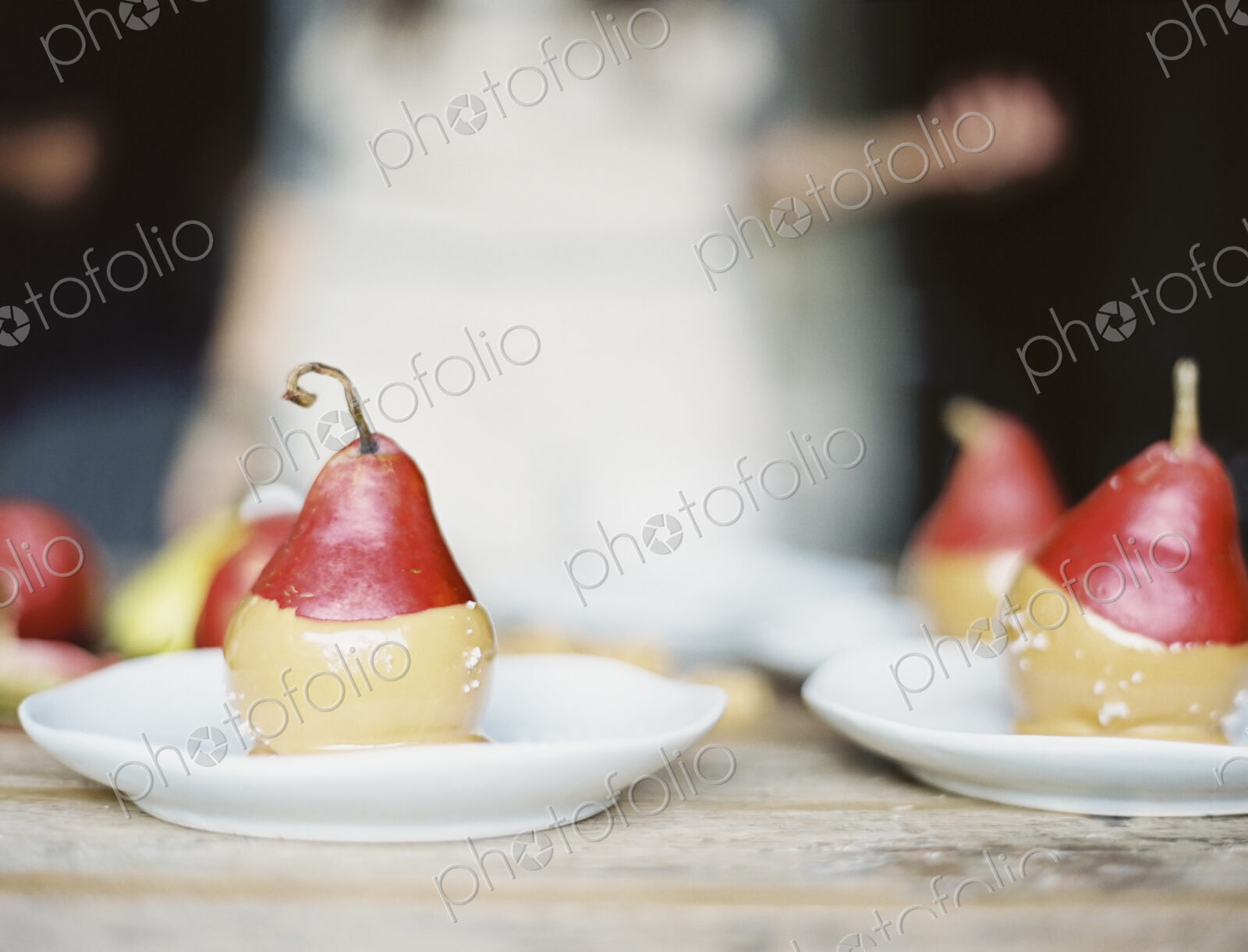 A woman in a domestic kitchen. Fresh organic pears dipped into a sauce for dessert…
