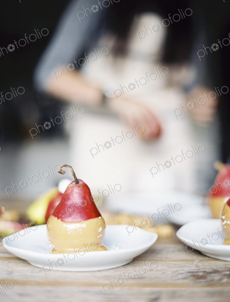 A woman in a domestic kitchen. Fresh organic pears dipped into a sauce for dessert…
