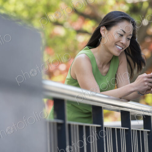 A woman in a green dress outdoors in a city park under trees in blossom. A woman in a green dress outdoors in a city park under trees in blossom.