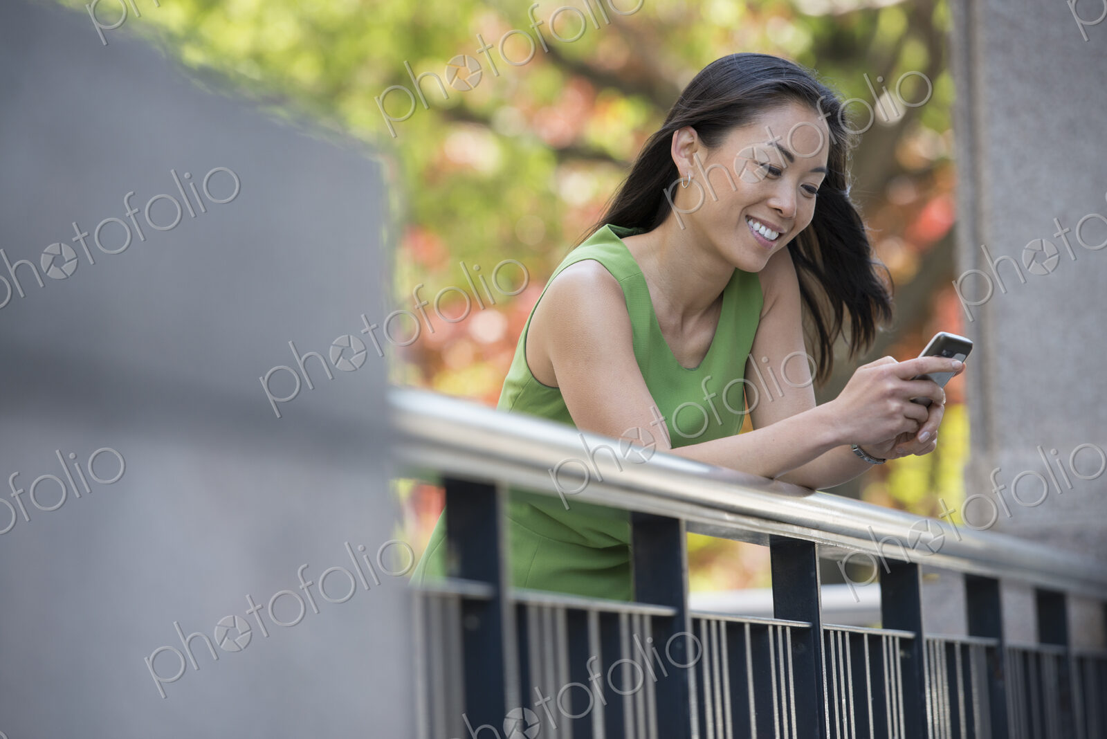 A woman in a green dress outdoors in a city park under trees in blossom.