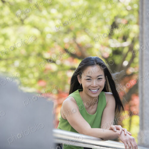 A woman in a green dress outdoors in a city park under trees in blossom. A woman in a green dress outdoors in a city park under trees in blossom.