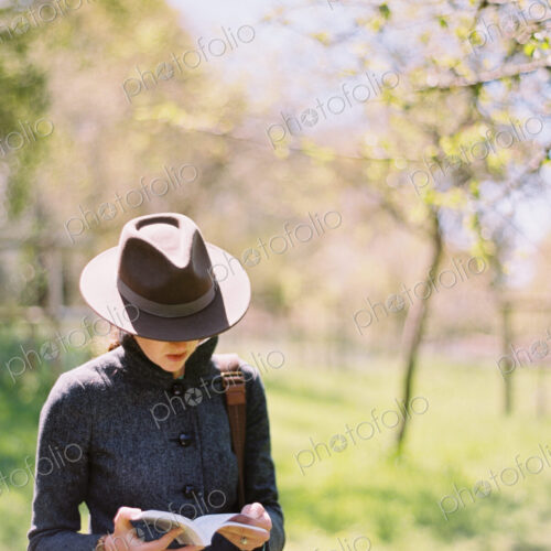 A woman in a hat, reading a book.