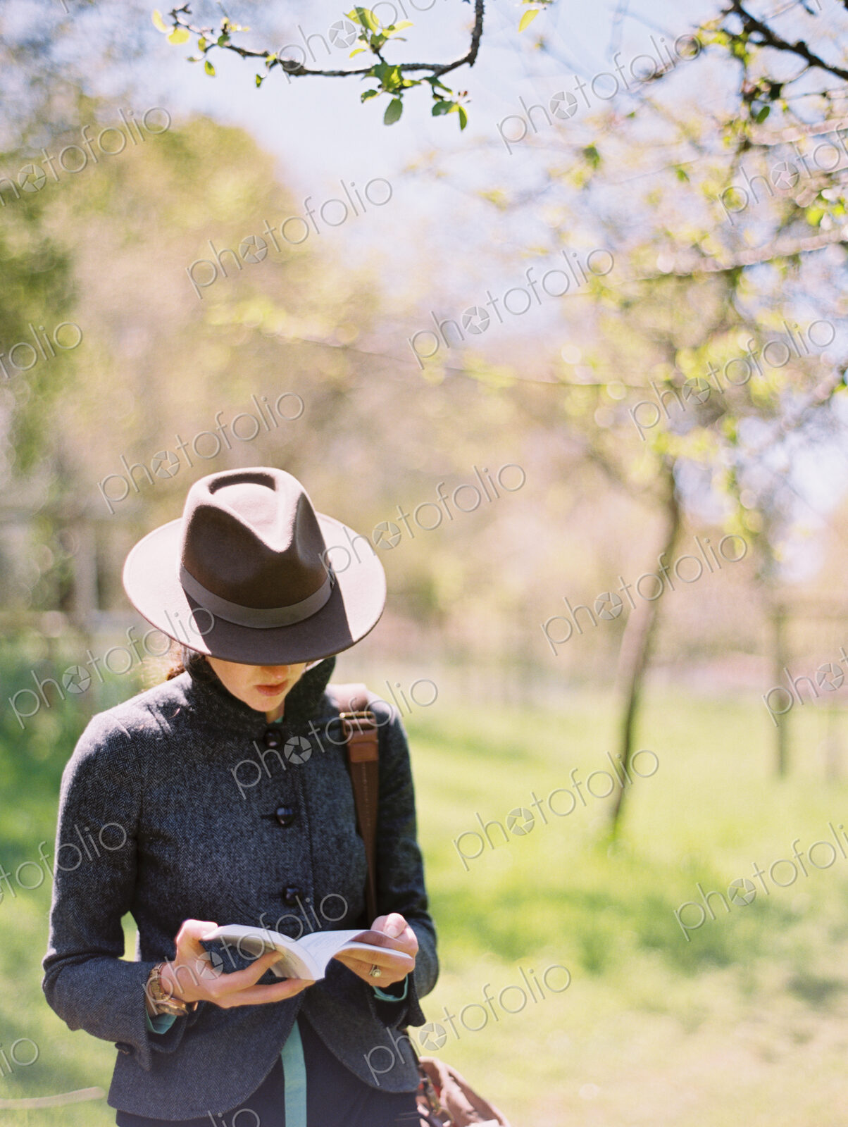 A woman in a hat, reading a book.