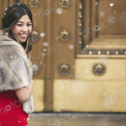A woman in a red dress and fur stole looking over her shoulder laughing.