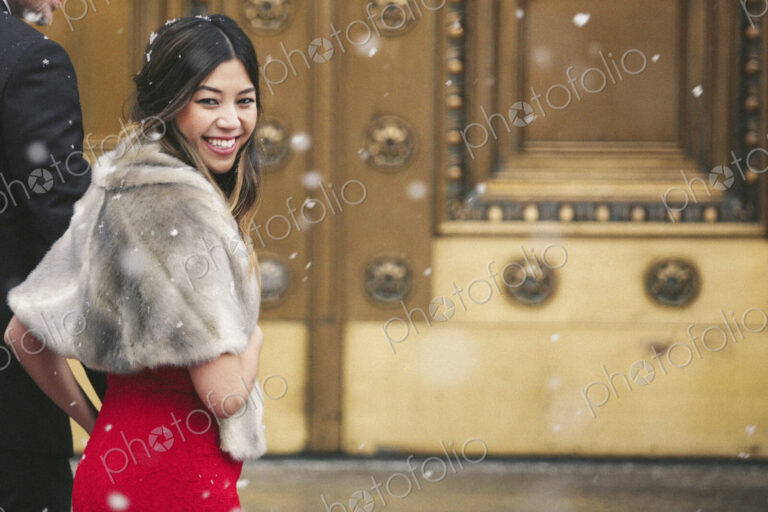 A woman in a red dress and fur stole looking over her shoulder laughing.