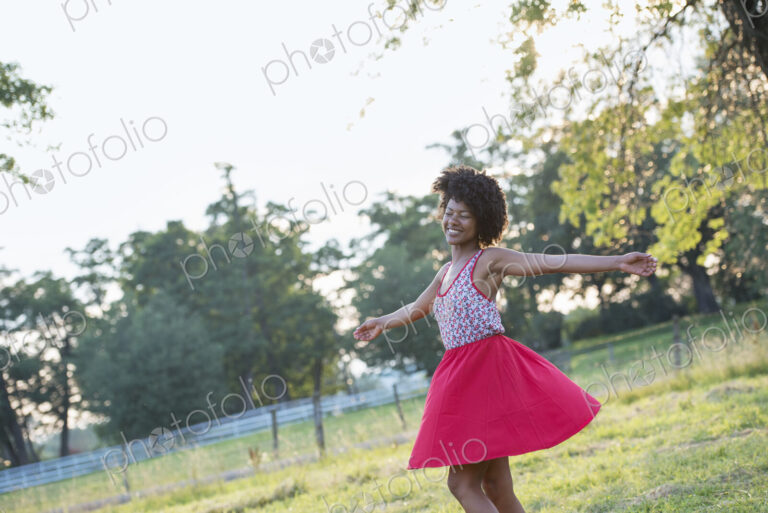 A woman in a red skirt, whirling around in the open air, with her arms outstretched.