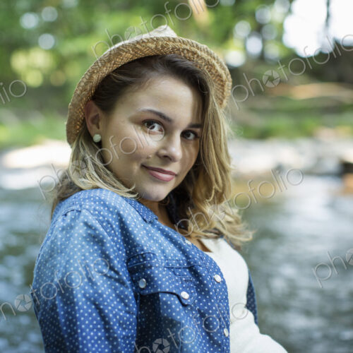 A woman in a straw hat on a river bank. A woman in a straw hat on a river bank.
