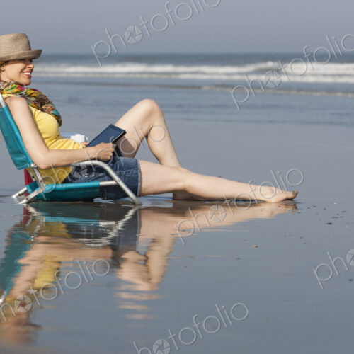 A woman in a sunhat and scarf on the beach on the New Jersey Shore, sitting holding a… A woman in a sunhat and scarf on the beach on the New Jersey Shore, sitting holding a…