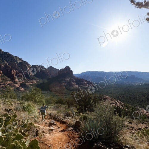 A woman in a sunhat walking up a trail in the Sedona national park, hiking in the…