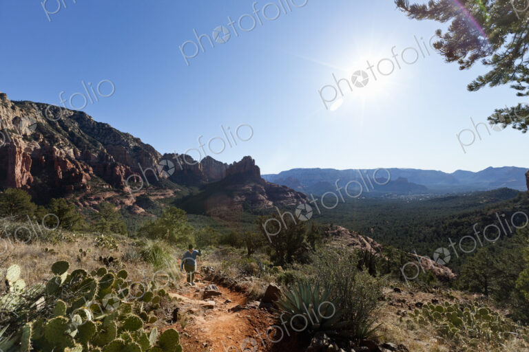 A woman in a sunhat walking up a trail in the Sedona national park, hiking in the…