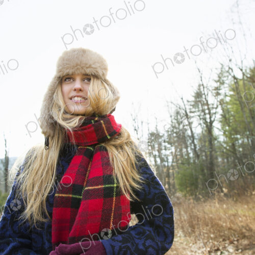 A woman in a warm furry hat and a big red tartan scarf, outdoors in the winter. A woman in a warm furry hat and a big red tartan scarf, outdoors in the winter.