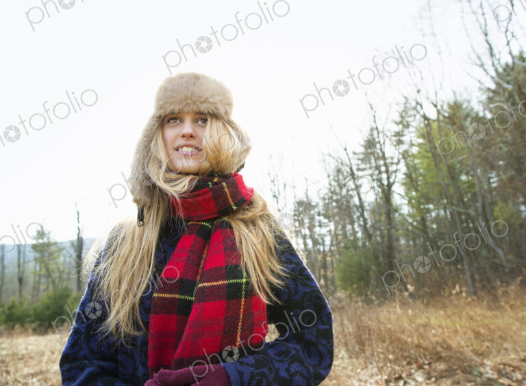 A woman in a warm furry hat and a big red tartan scarf, outdoors in the winter.