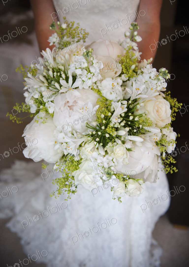 A woman in a white dress, a bride holding a bridal bouquet of white flowers, large…