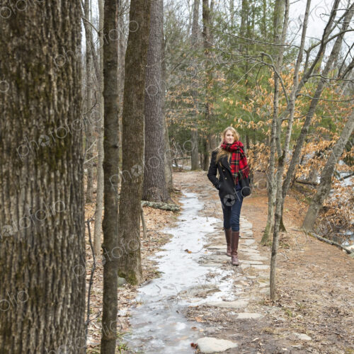 A woman in a winter coat and red scarf walking down a woodland path, in winter. A woman in a winter coat and red scarf walking down a woodland path, in winter.