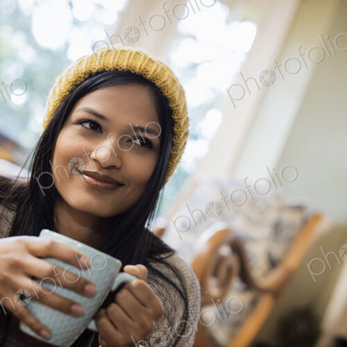 A woman in a woolly hat holding a mug in her hands. A woman in a woolly hat holding a mug in her hands.