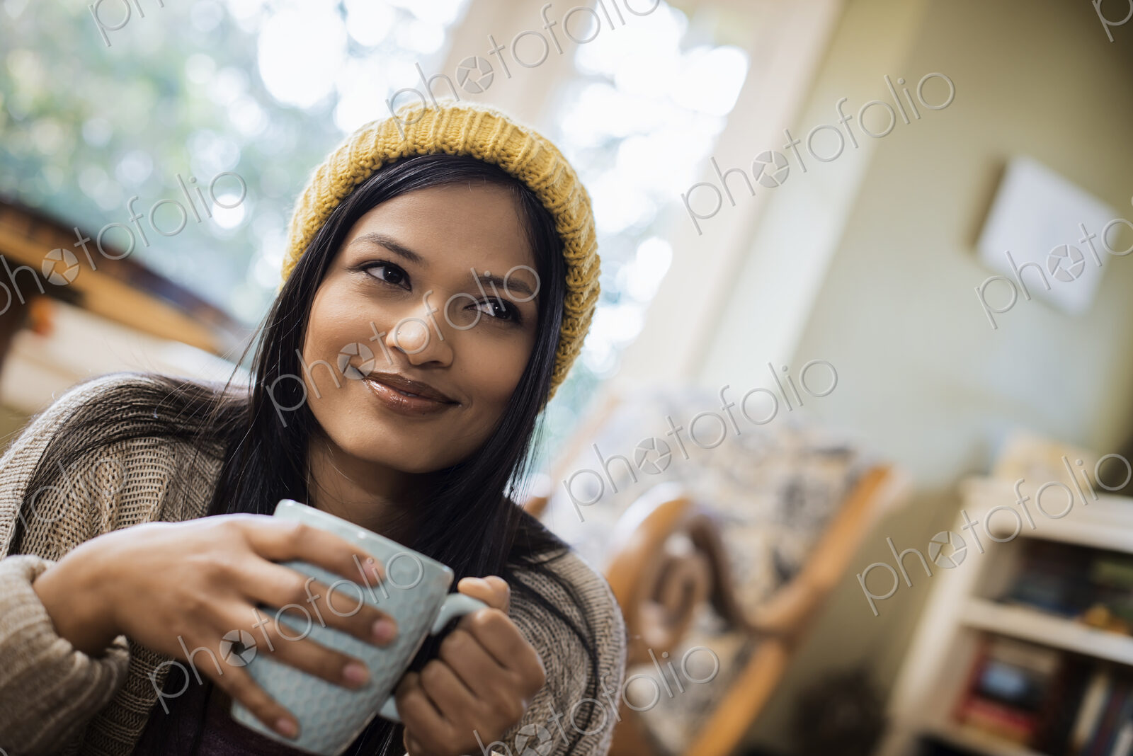 A woman in a woolly hat holding a mug in her hands.