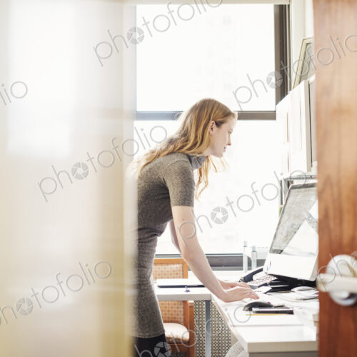 A woman in an office, seen through an open door. A woman in an office, seen through an open door.