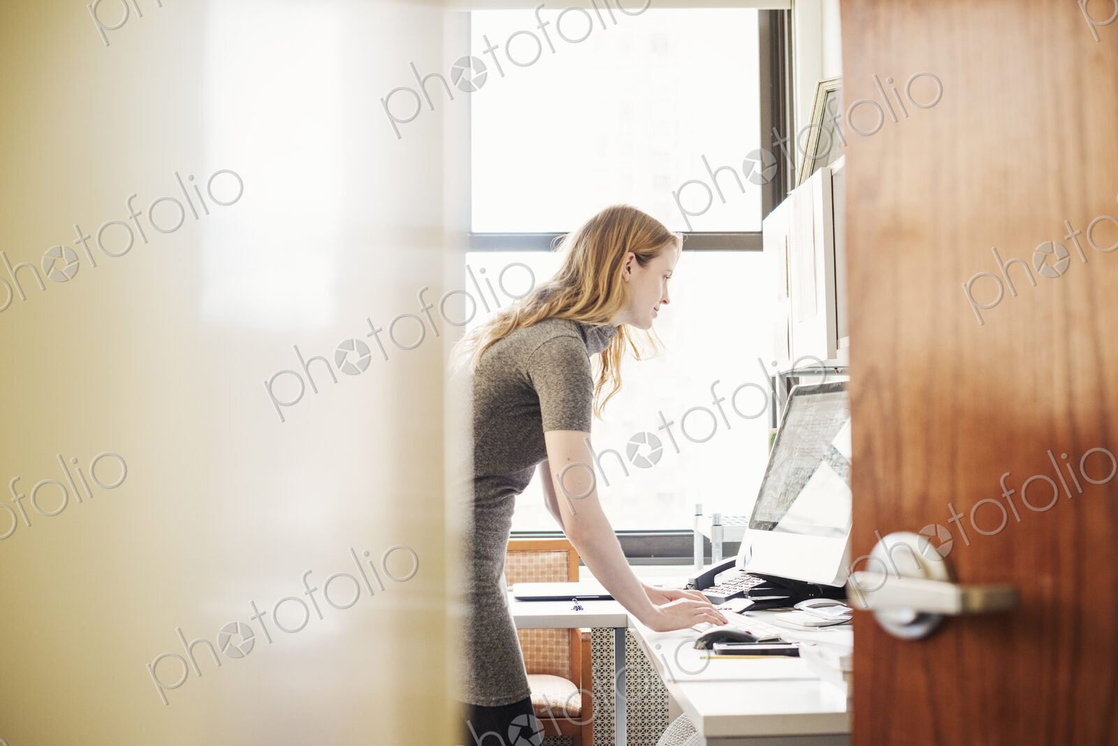 A woman in an office, seen through an open door.