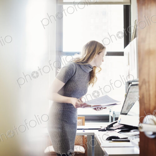 A woman in an office, seen through an open door. A woman in an office, seen through an open door.