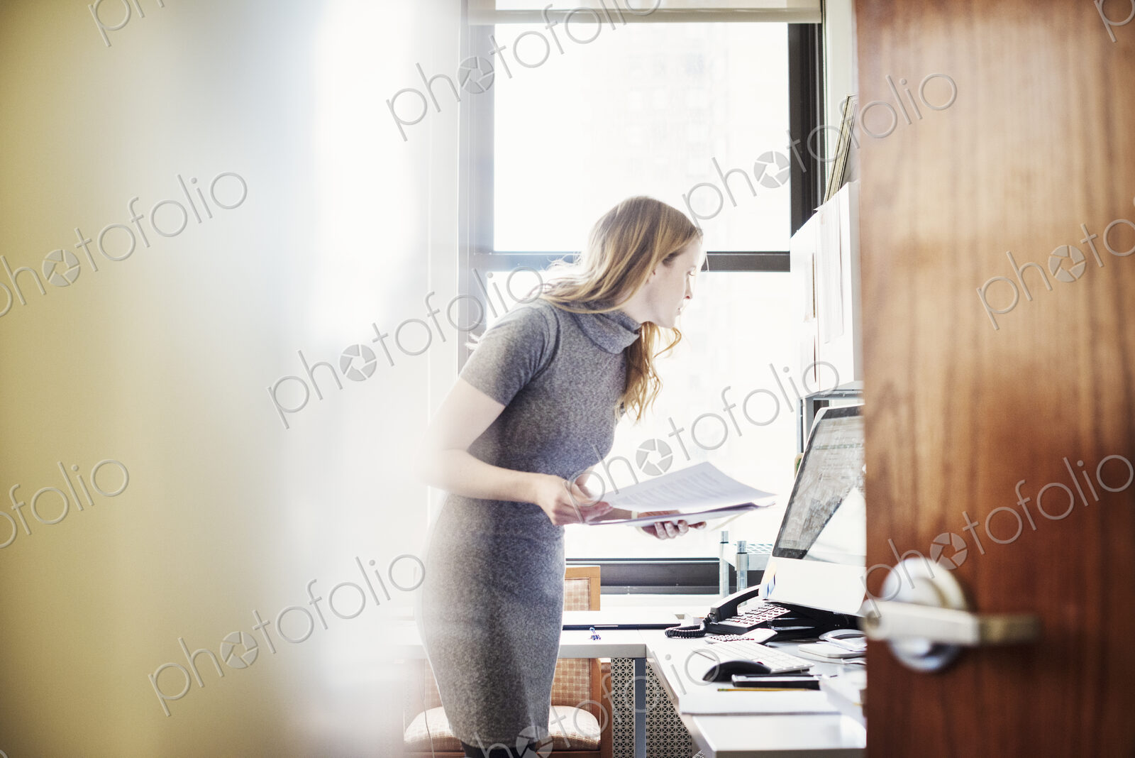 A woman in an office, seen through an open door.