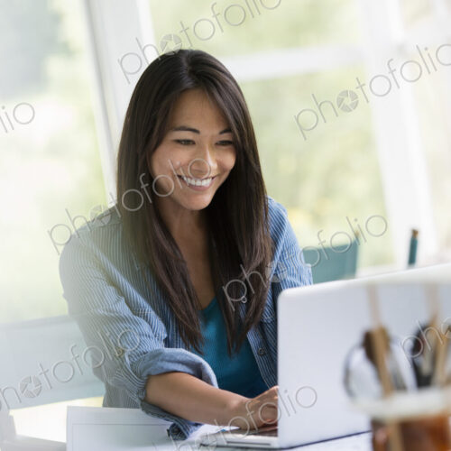 A woman in an office, working at a laptop computer.