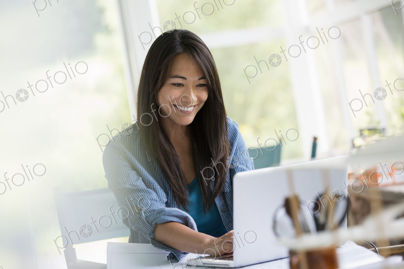 A woman in an office, working at a laptop computer.