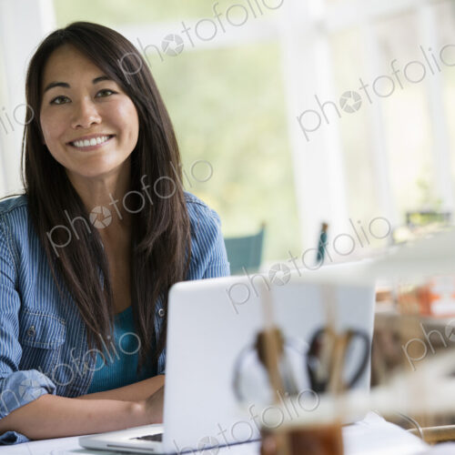A woman in an office, working at a laptop computer.