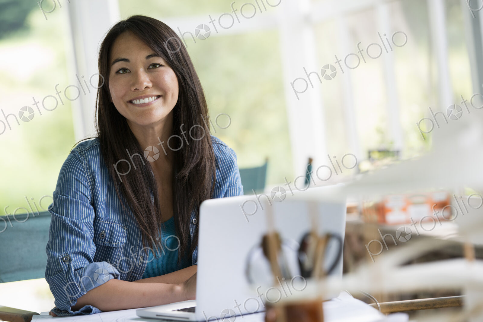 A woman in an office, working at a laptop computer.