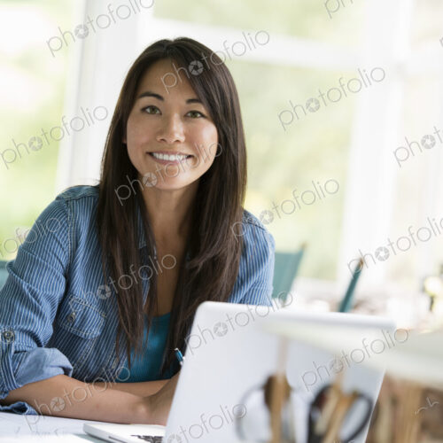 A woman in an office, working at a laptop computer.
