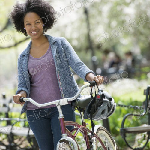 A woman in casual clothes in the park pushing a bicycle. A woman in casual clothes in the park pushing a bicycle.