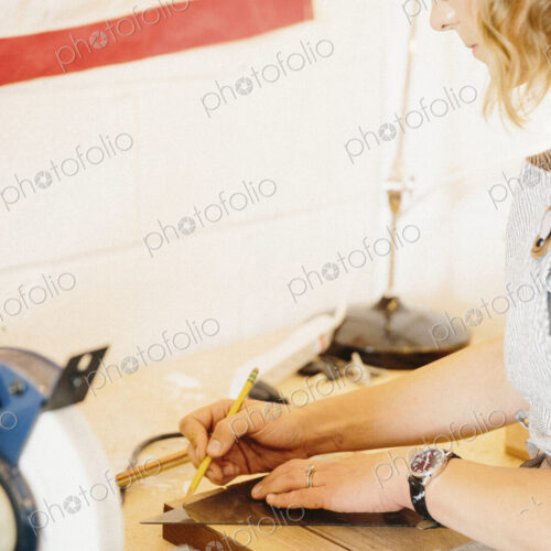 A woman in her workshop using a template to mark wooden blocks.