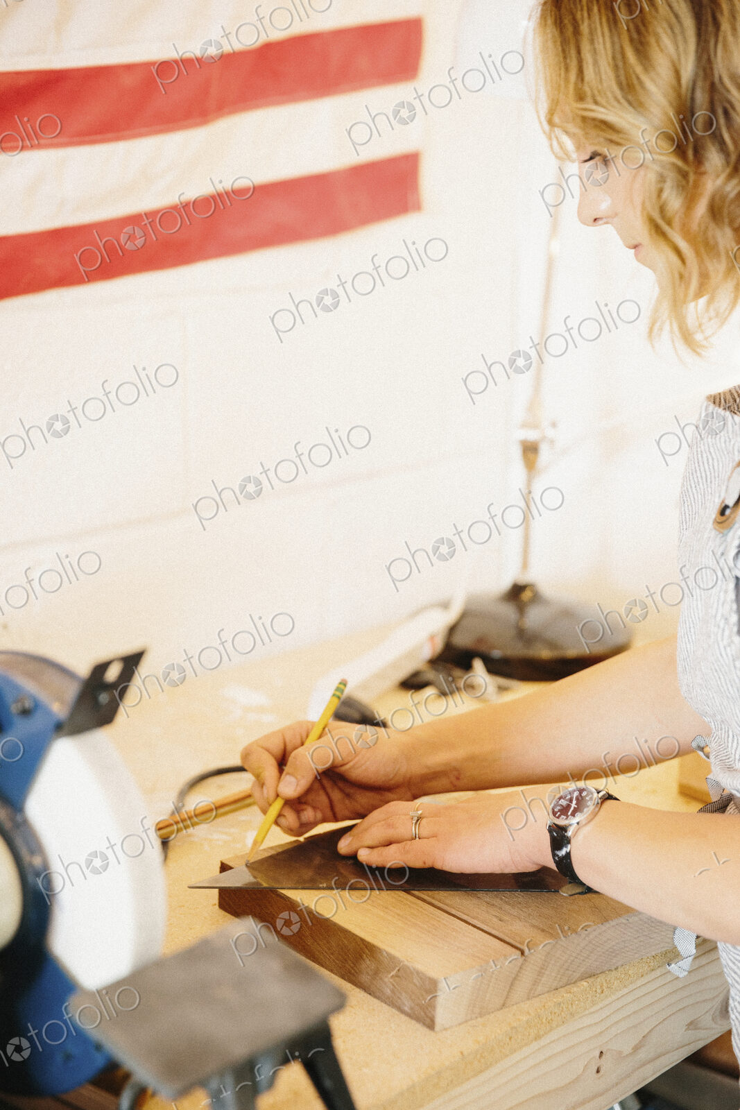 A woman in her workshop using a template to mark wooden blocks.