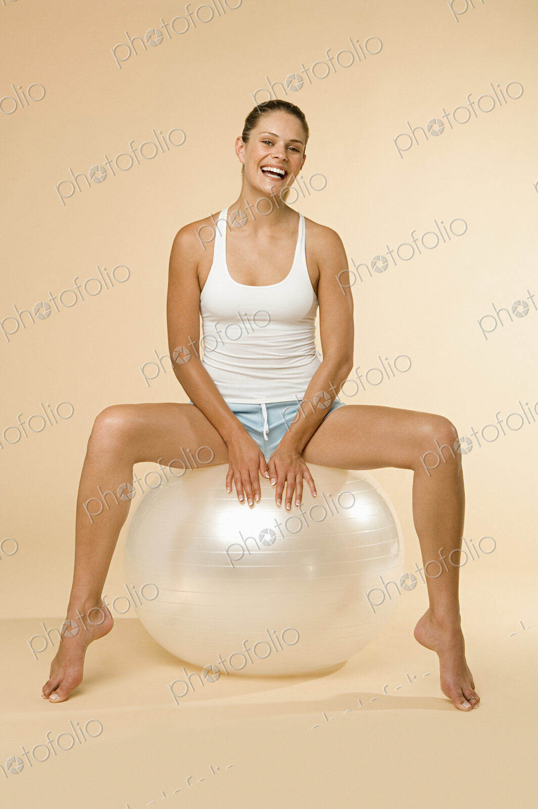 A woman in vest and shorts sitting on an exercise ball.