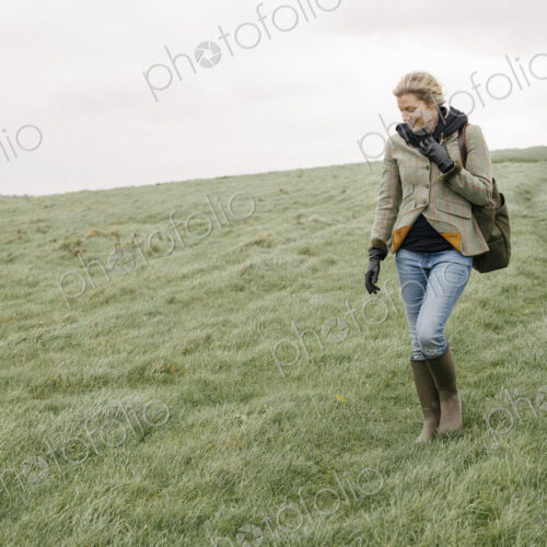 A woman in warm coat and gloves walking across open country, grassland and moors. A woman in warm coat and gloves walking across open country, grassland and moors.