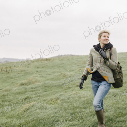 A woman in warm coat and gloves walking across open country, grassland and moors. A woman in warm coat and gloves walking across open country, grassland and moors.
