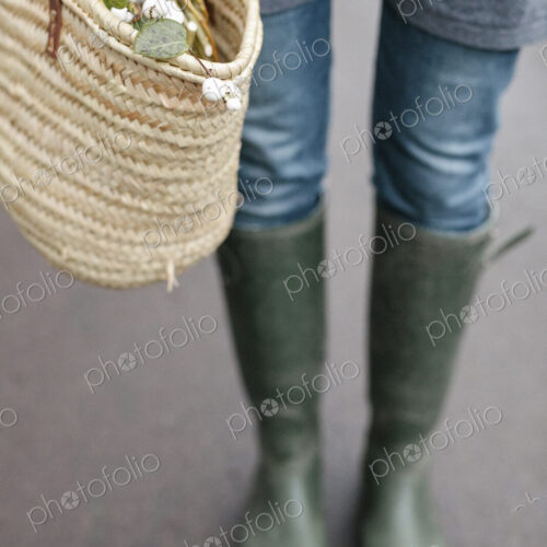 A woman in wellingtons and jeans carrying a basket. A woman in wellingtons and jeans carrying a basket.