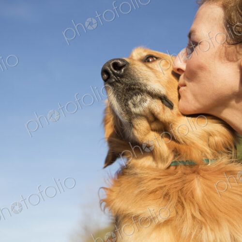 A woman kissing a pet dog on the cheek. A woman kissing a pet dog on the cheek.