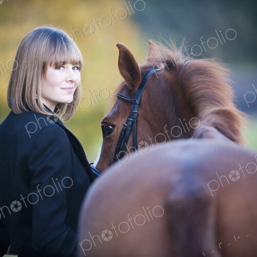 A woman leading a bay horse by the bridle.