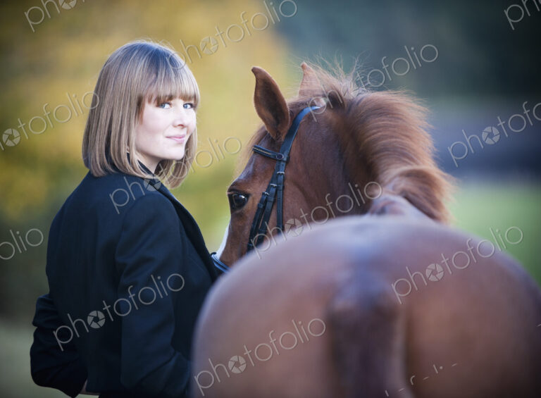 A woman leading a bay horse by the bridle.
